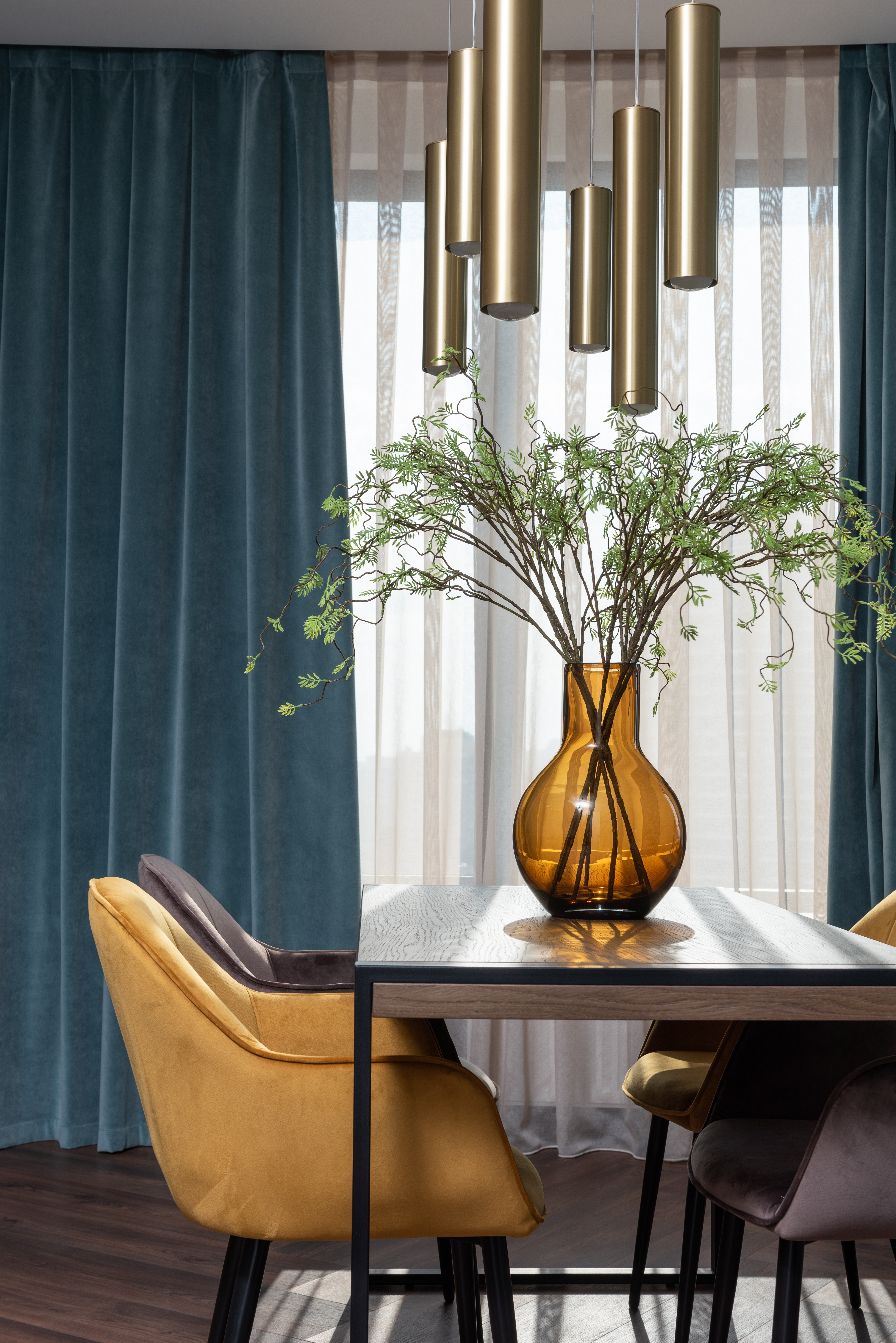 pendant lights suspended from the ceiling over a vase table and yellow chair